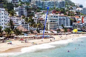 Paisagem costeira com edifícios altos, uma praia e um céu azul límpido.