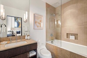 Un baño moderno con un espejo grande, un lavabo, un inodoro y una ducha con cerramiento de vidrio.