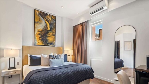 Une chambre d’hôtel moderne avec un grand lit, un tableau au mur, un miroir et un bureau.