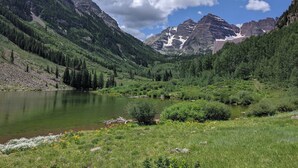 Un paysage de montagne avec un lac, une forêt dense et des montagnes rocheuses.