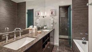 Une salle de bain moderne dotée d’un grand meuble-lavabo, de deux vasques, d’une douche et d’un espace de douche clos par des parois de verre.