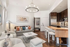 Una sala de estar moderna con sofá, una mesa de centro y una zona de comedor con taburetes de bar.