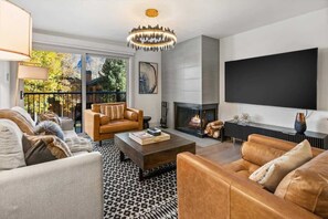 A modern living room with a fireplace, leather sofas, a coffee table, and a large TV. - Renovated 2 BR - 2 BA In Town with AC! (Aspen)