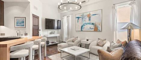 A modern living room with a dining area, a large abstract painting, and a flat-screen TV.