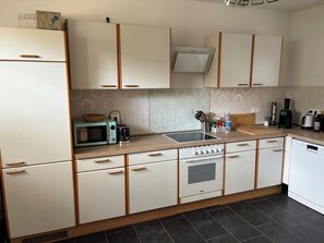 A modern kitchen with white cabinets, a microwave, toaster, and a stove. - Cozy apartment with large garden and perfect location between the mountains and the sea (Liebenfels)