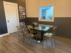 A dining area with a glass table and metal chairs, a door, and a window with a view. - 3BDR Entire House 1BLK to River/5min Walk to DTWN (Saskatoon)