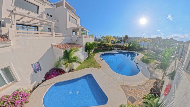Propiedad residencial con dos piscinas, un porche cubierto y vista a una zona residencial.