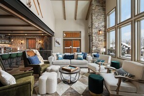 A spacious living area with a stone accent wall, large windows, and a cozy seating arrangement. - *New Build* Black Eagle Ski-In/Ski-Out Retreat (Big Sky)