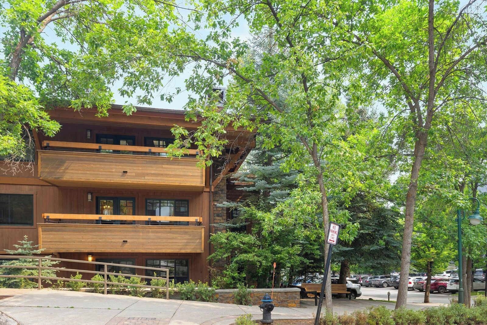 A multi-story building with a wooden facade, a fire hydrant, and a 'No Parking' sign.