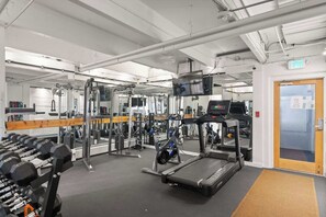 A gym with exercise equipment, a mirror, and an exit door.