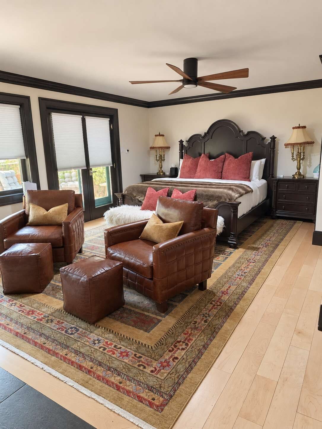 A bedroom with a large bed, two nightstands, a ceiling fan, and a patterned rug.
