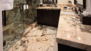 Une salle de bain dotée d’une douche à parois de verre, d’un meuble-lavabo en marbre et d’un grand miroir.