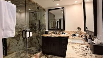 Un baño con ducha de vidrio, tocador de mármol y un espejo grande.