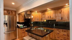 Une cuisine moderne avec des meubles en bois, un réfrigérateur en acier inoxydable et un îlot central doté de tabourets.