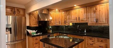 Una cocina moderna con armarios de madera, un refrigerador de acero inoxidable y una isla central con taburetes.