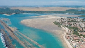 An aerial view of a coastal area with a beach, a town, and a large body of water. - Flat 106 S Iloa Residence - Barra de São Miguel, Alagoas, vacation rental (Barra de São Miguel)