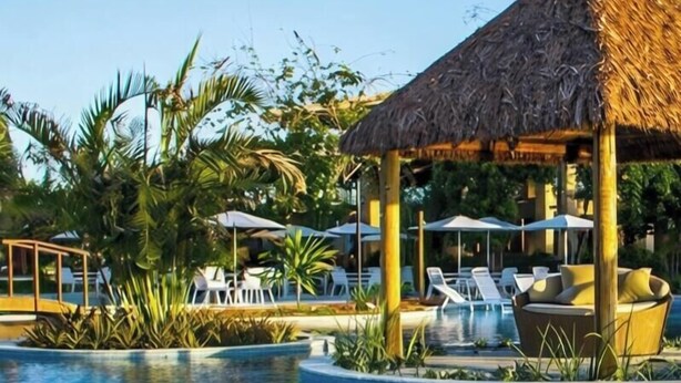 A pool with lounge chairs and a thatched-roof pavilion. - Flat 106 S Iloa Residence - Barra de São Miguel, Alagoas, vacation rental (Barra de São Miguel)
