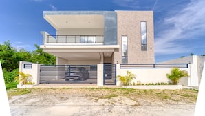 A modern two-story house with a flat roof, a balcony, and a gated entrance. - Modern Villa w/ Pool & Garden, 1 Free Excursion (Punta Cana)