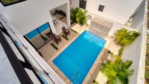 A modern building with a swimming pool, outdoor seating, and palm trees. - Modern Villa w/ Pool & Garden, 1 Free Excursion (Punta Cana)