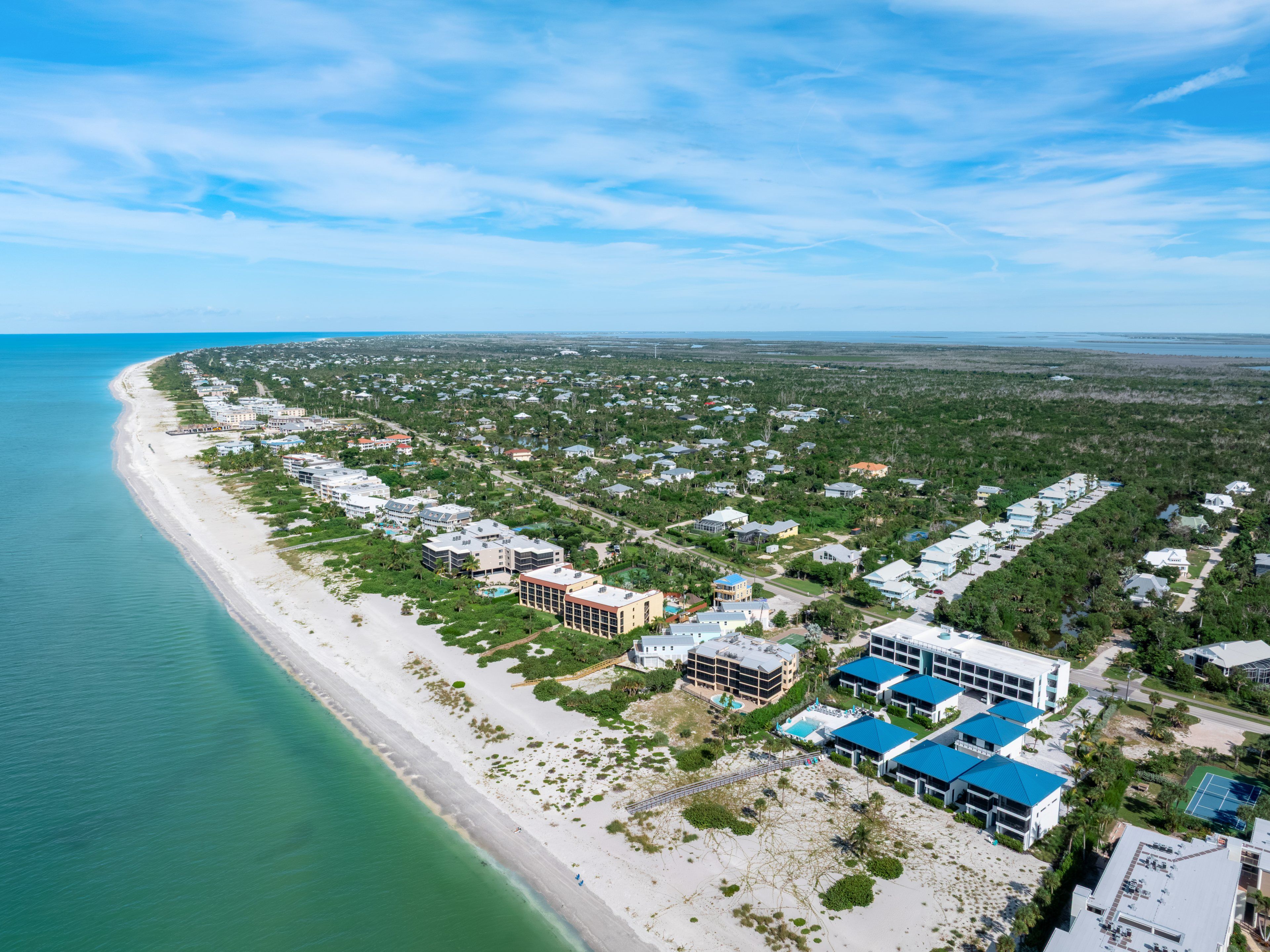 An aerial view of a coastal residential area with beachfront properties and a dense cluster of houses inland.