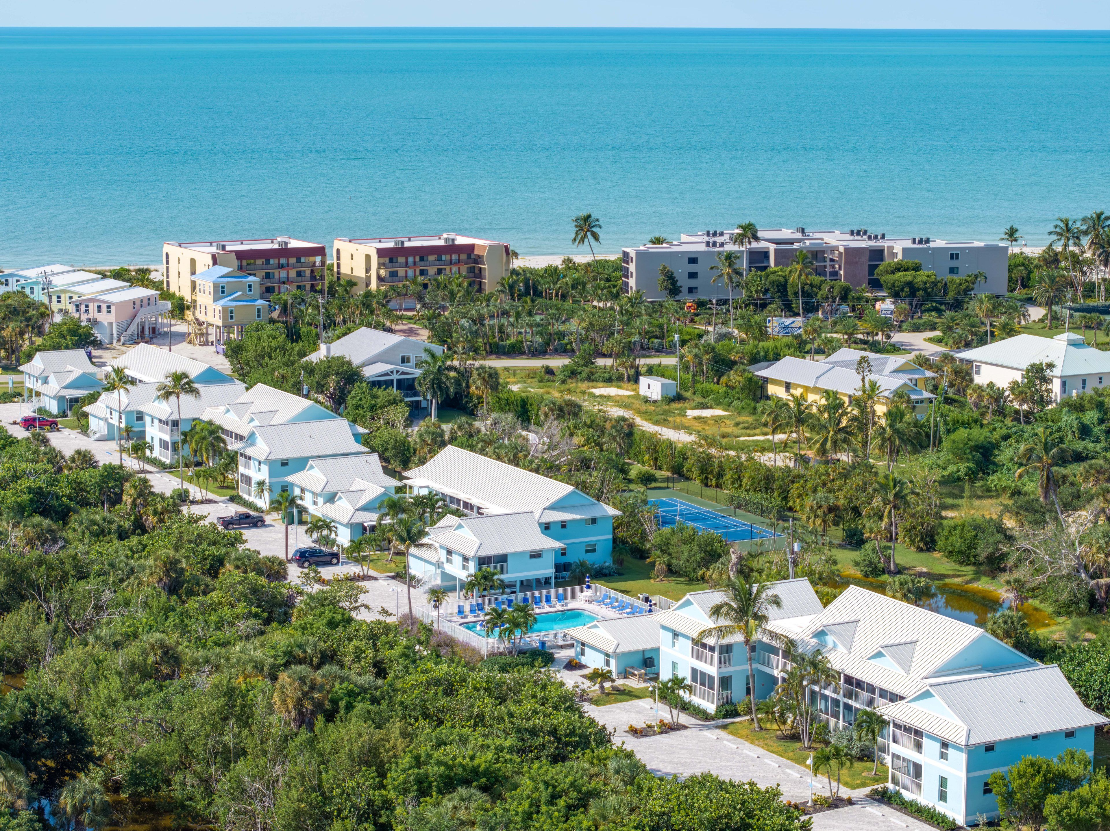 A resort with multiple buildings, a swimming pool, and a view of the ocean.