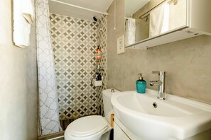 A bathroom with a toilet, sink, shower, and patterned wallpaper. - Harbor View Apartment in Mykonos Town (Mykonos)