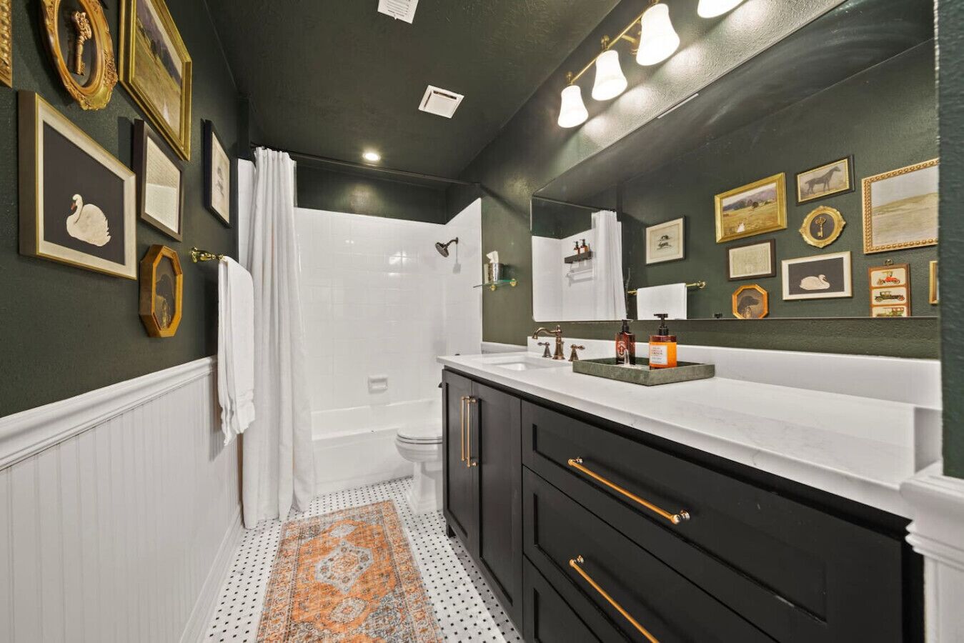 Une salle de bain avec une douche, un lavabo, un miroir et des tableaux encadrés accrochés aux murs.