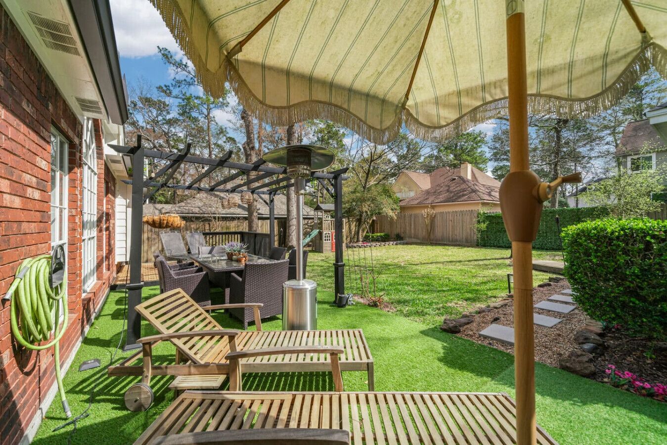 Een terras met buitenmeubilair, een pergola en een waterslang.