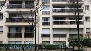 A multi-story residential building with balconies, a gated entrance, and a paved walkway. - Parisian studio in the 17th district, fully equipped with balcony (Paris)