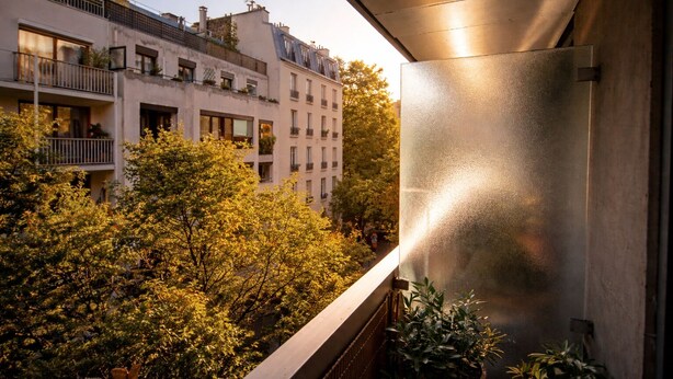 A balcony with a view of a tree-lined street and adjacent buildings. - Parisian studio in the 17th district, fully equipped with balcony (Paris)