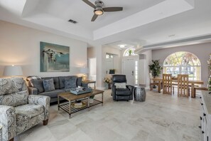 A spacious living area with a sofa, armchairs, a coffee table, and a dining table. - Private Pool Retreat / Pet-Friendly / Sleeps 6 (Port Orange)