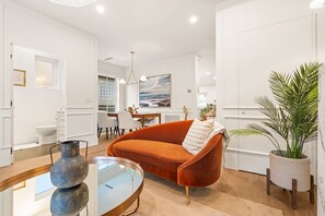 A modern living room with a sofa, a glass coffee table, and a potted plant. - Brand-New Sun-Drenched Kits Home - Rooftop Deck (Vancouver)