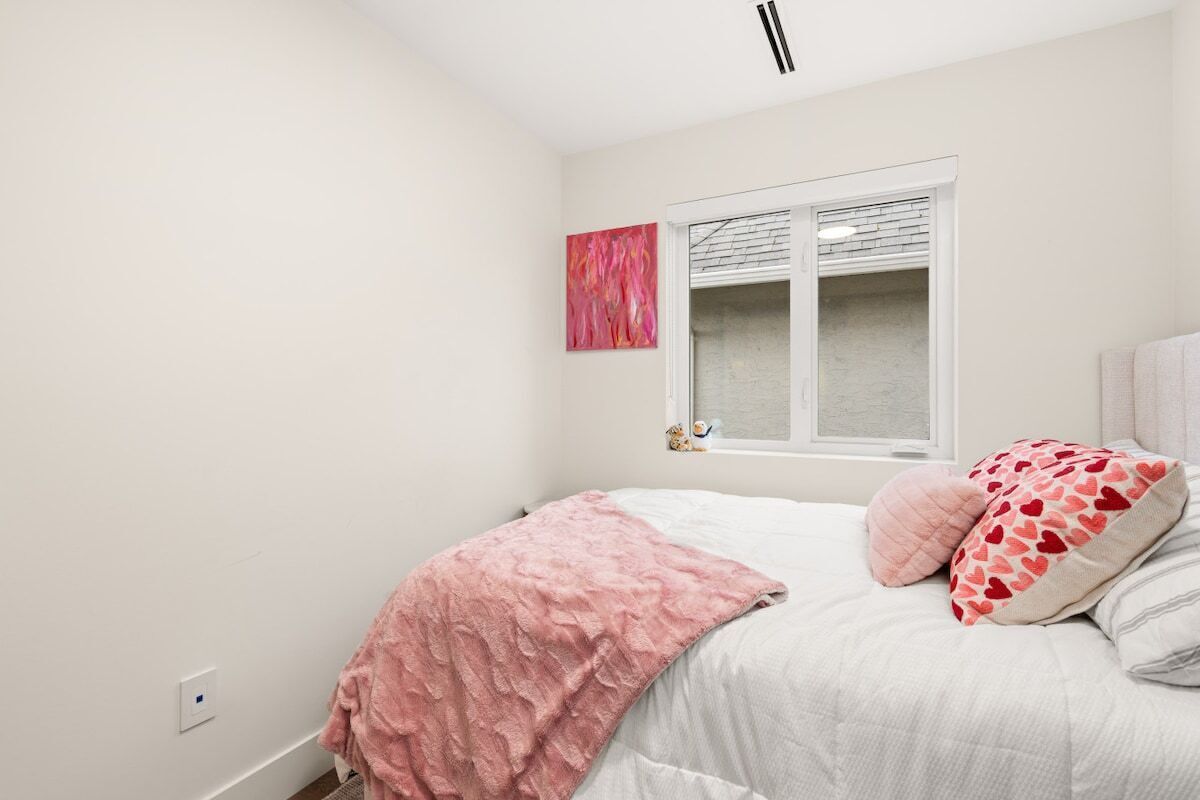 Un dormitorio con cama, ventana y una obra de arte colgada en la pared.