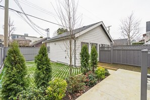 A residential backyard with a house, a lawn, and a wooden fence. - Brand-New Sun-Drenched Kits Home - Rooftop Deck (Vancouver)