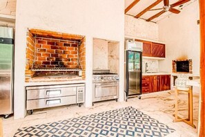 A kitchen with a brick oven, stainless steel appliances, and a patterned floor. - Kasa Uh May (Francisco Uh May)