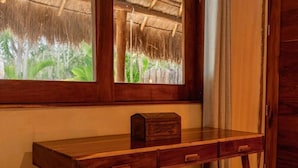 A wooden desk with drawers and a small box, positioned next to a window with a view of greenery. - Kasa Uh May (Francisco Uh May)