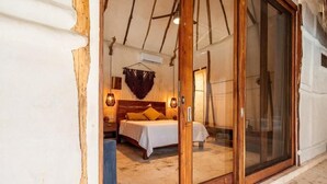 A bedroom with a bed, a hanging light, and a sliding glass door. - Kasa Uh May (Francisco Uh May)