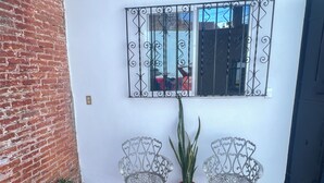 A brick wall, two metal chairs, a potted plant, and a window with a metal grille. - Casita on quiet street just 15 minute walk to historic center. (Oaxaca de Juárez)