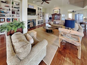 A living room with a fireplace, a television, a sofa, a coffee table, and a bookshelf. - Galveston Baywatch (Galveston)