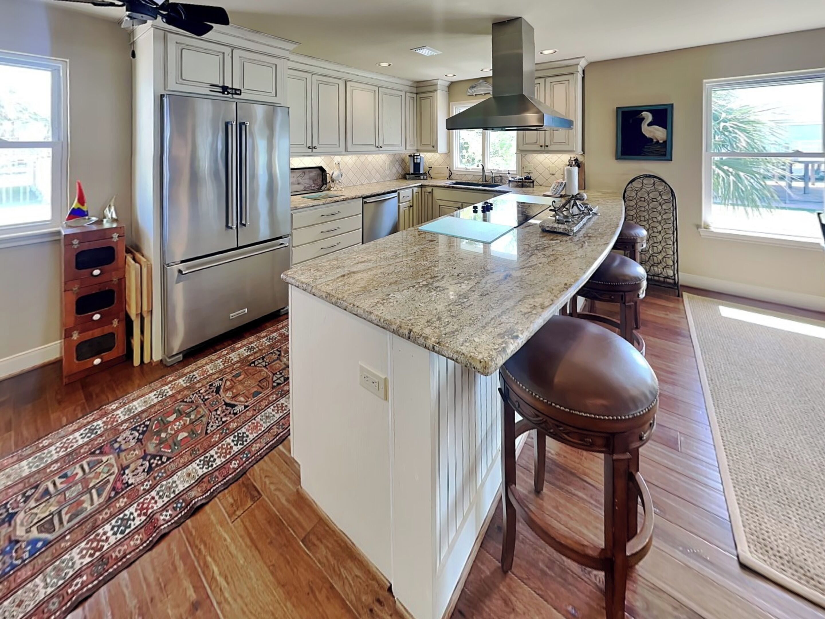 A kitchen with a large island, stainless steel appliances, and a view of the outdoors.