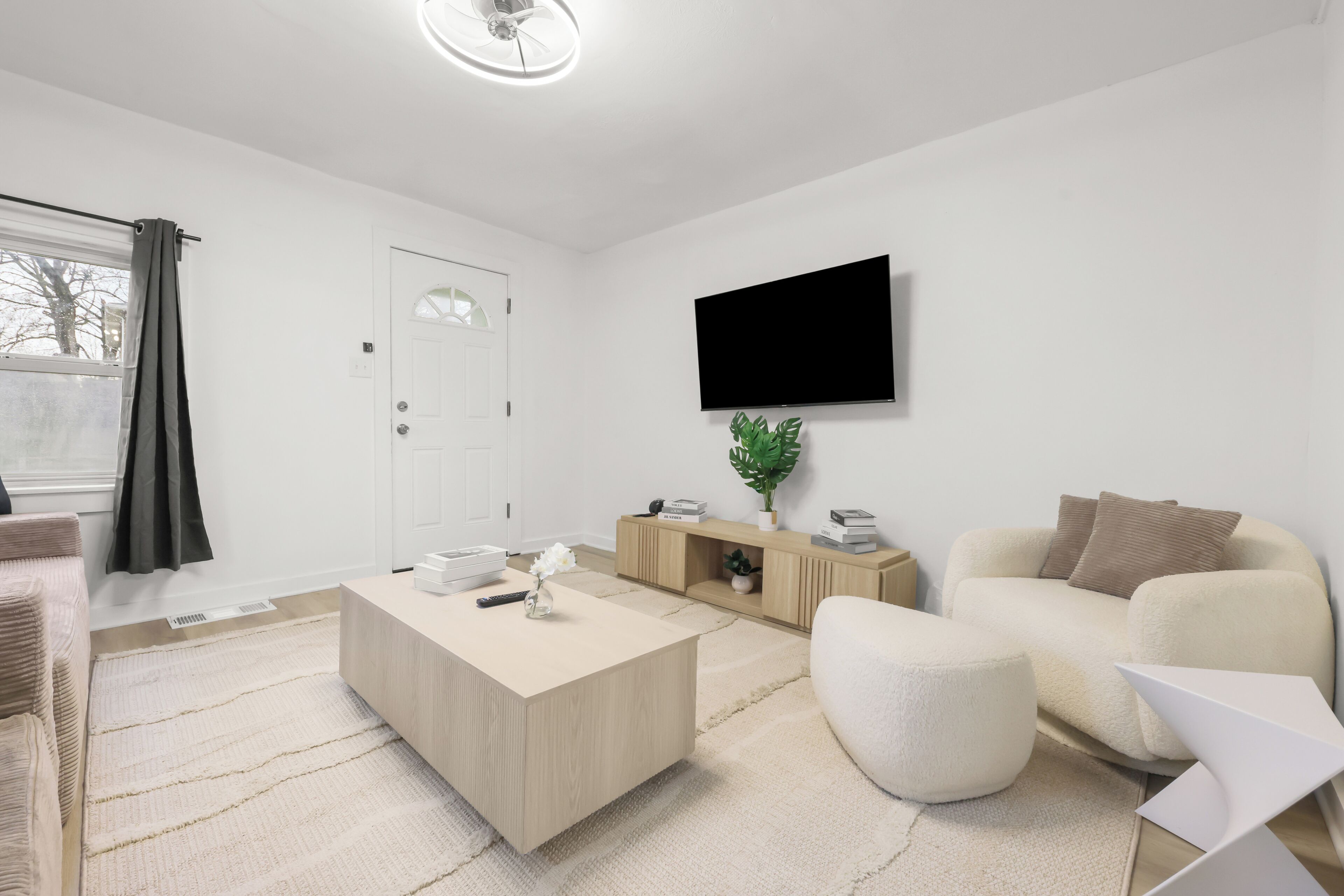A modern living room with a flat-screen TV, a beige sofa, a coffee table, and a wooden sideboard.