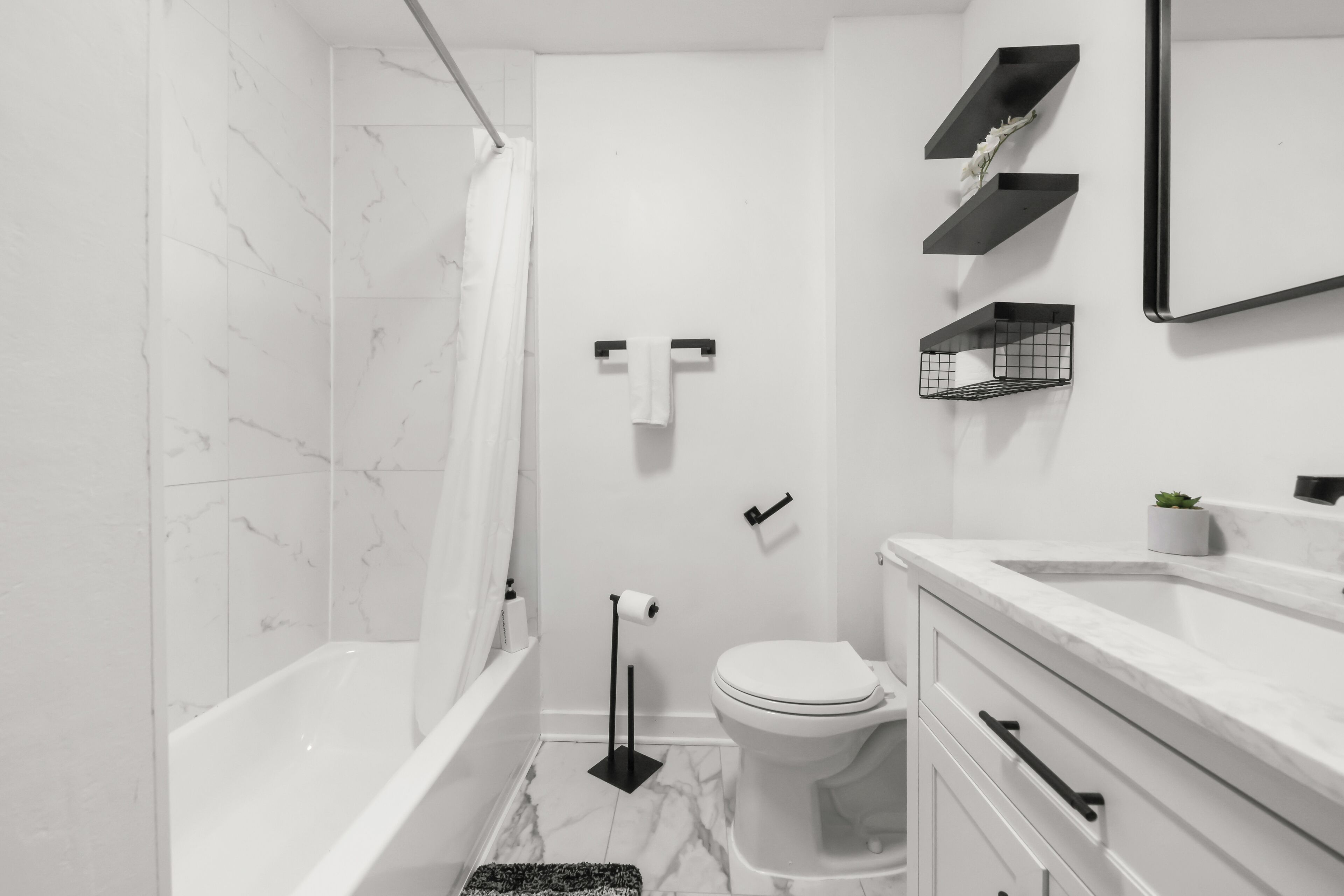 Une salle de bain moderne équipée d’une baignoire, de toilettes et d’un meuble-lavabo avec un miroir.