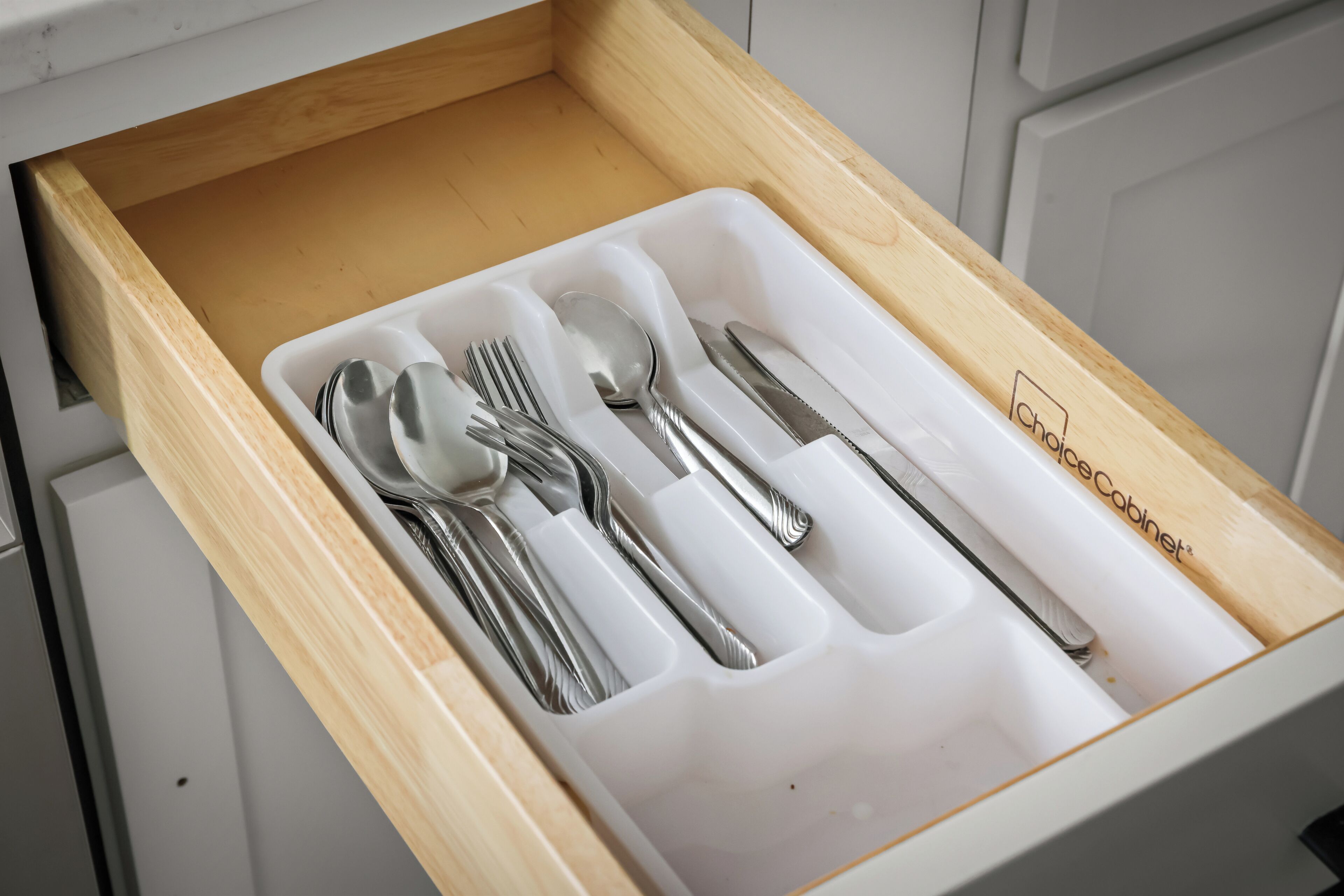 A drawer with compartments containing utensils.