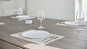 A dining table set with white plates, silverware, and wine glasses, with a wooden table and a white wall in the background. - Modern 3BR Home Game Room Pool & Ping-Pong (Akron)