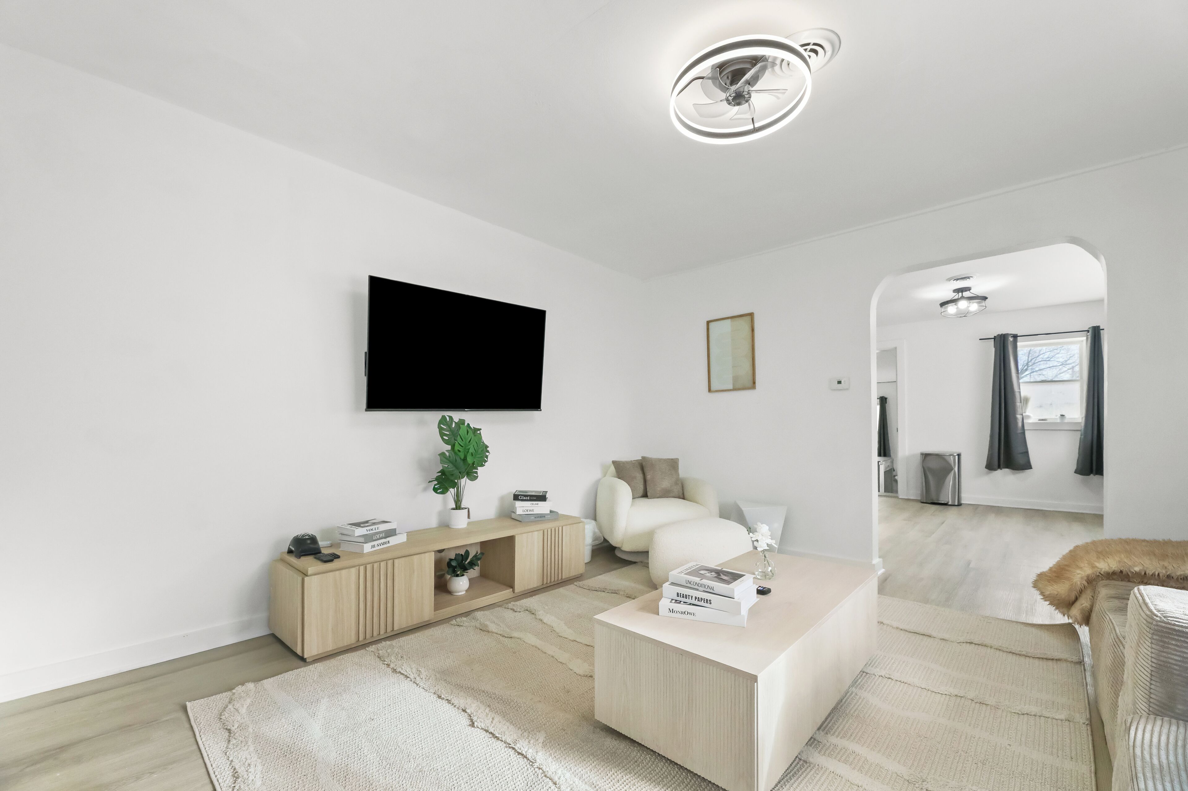 A modern living room with a flat-screen TV, a wooden console, a sofa, a coffee table, and a mirror.