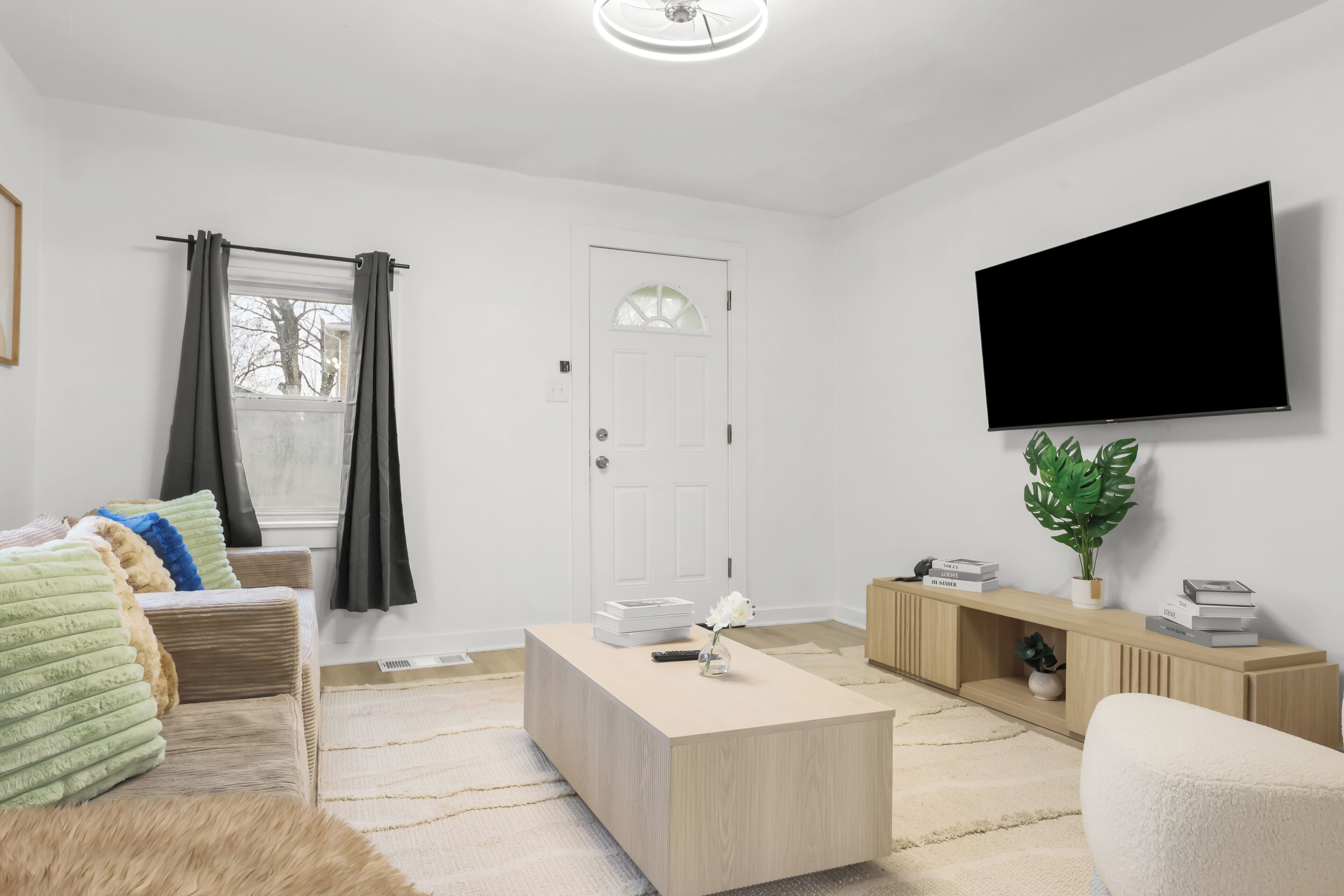 A modern living room with a sofa, coffee table, TV, and a door.