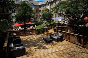 A wooden deck with outdoor seating, a staircase, and a building in the background. - 2BR King+Queen Suite w/ Kitchen | Free Breakfast (Vaughan)