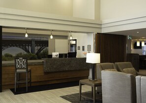 A hotel lobby with a reception desk, seating area, and a large window with a view of a bridge. - 2BR King+Queen Suite w/ Kitchen | Free Breakfast (Vaughan)