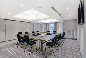 A conference room with a large table, chairs, a TV, and a window. - 1BR King Suite w/ Kitchen | Free Breakfast + Gym (Vaughan)