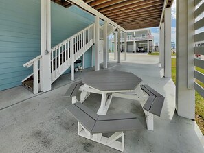 A covered outdoor area with a picnic table, a staircase, and a building with a light blue exterior. - Pelican's Landing (Rockport)